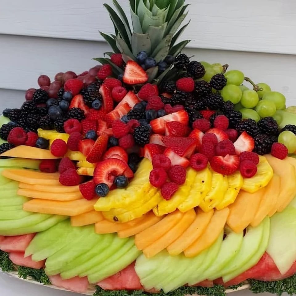 A large fruit platter with pineapple, strawberries, blueberries, raspberries, blackberries, grapes, cantaloupe, honeydew, and watermelon.